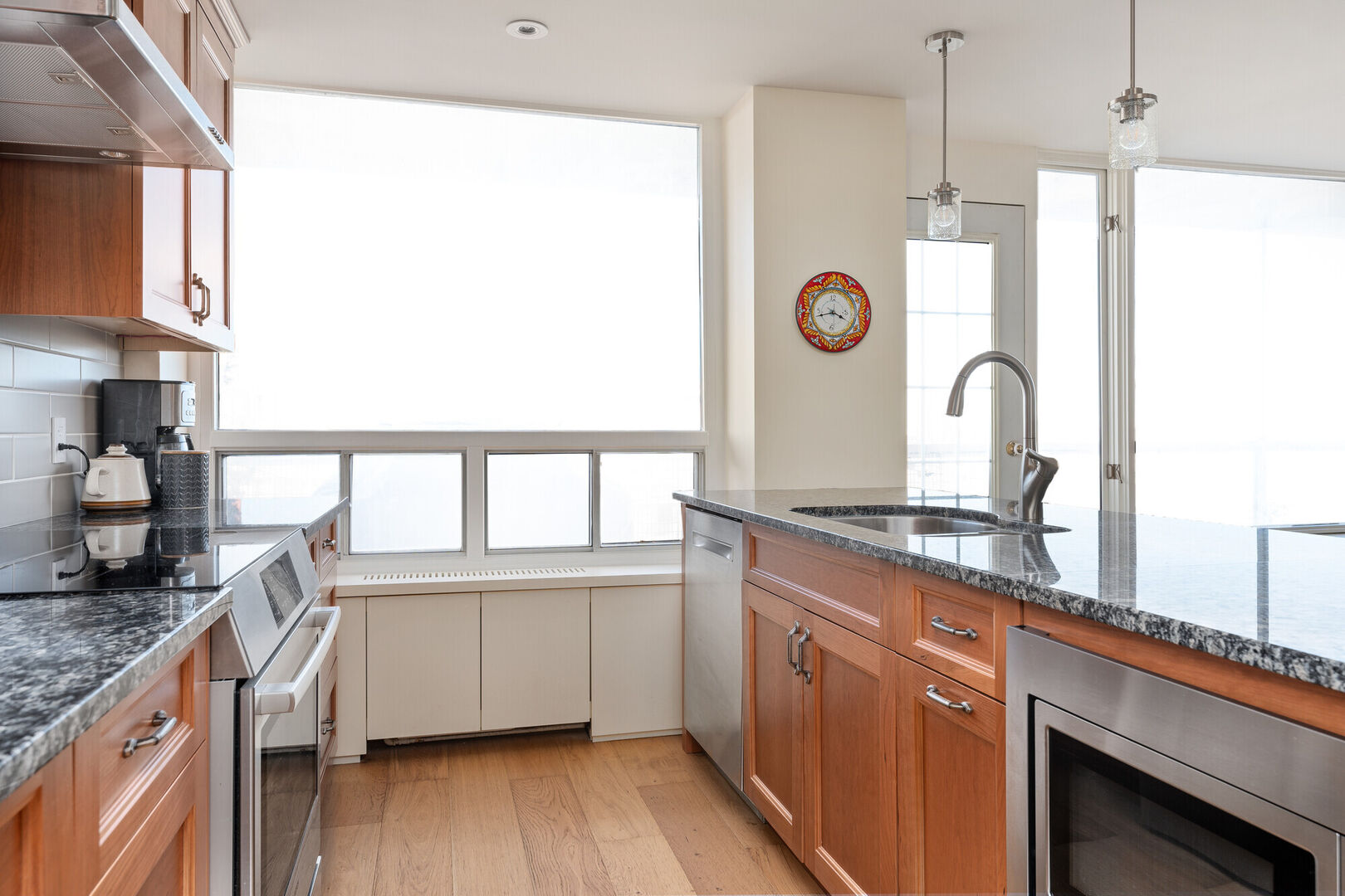Modern condo kitchen with oak cabinets and steel appliances with an open concept in SW Calgary interior design